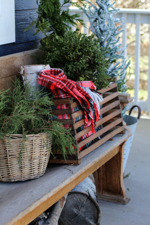 Vintage touches like plaid throws an old bins can make your Christmas porch feel cozy and collected!