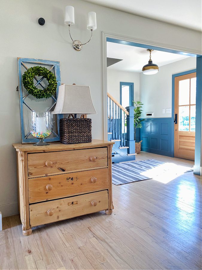 An old pine dresser with a lamp, window and colorful candy.