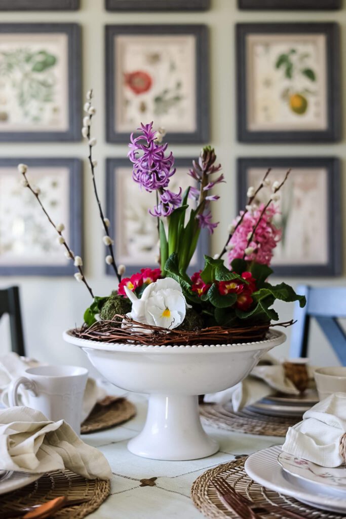 Let me show you how to decorate an easy cottage-style Easter table.  I will teach you how to make a pretty centerpiece with pots of fresh Spring flowers and bulbs and also make Easter napkin rings from clay.