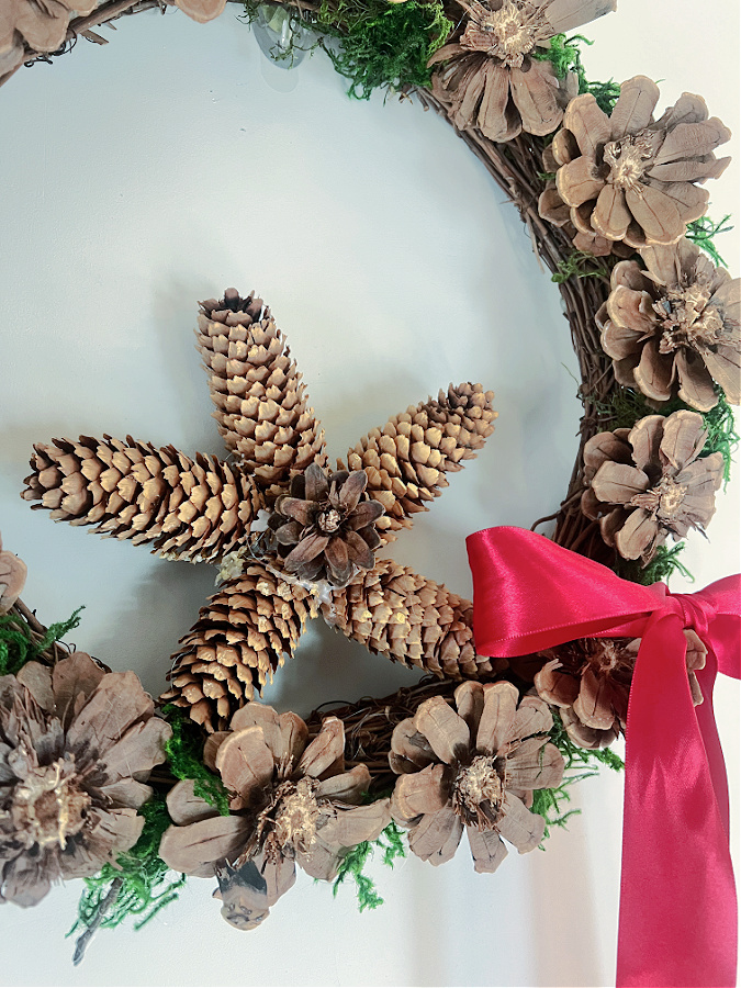 close up of pinecone flower wreath with star shaped pinecone ornament resting in it