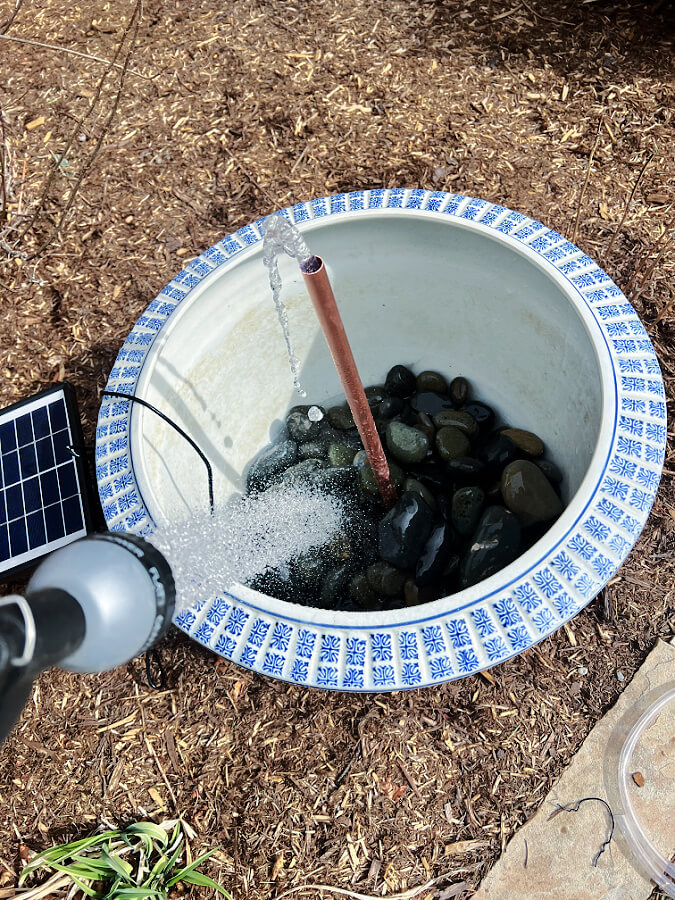 adding water to pot full of rocks for fountain