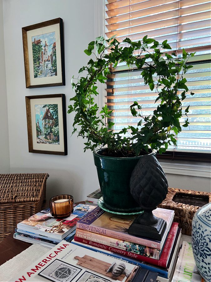 Green topiary surrounded by books on a table for early Fall decor