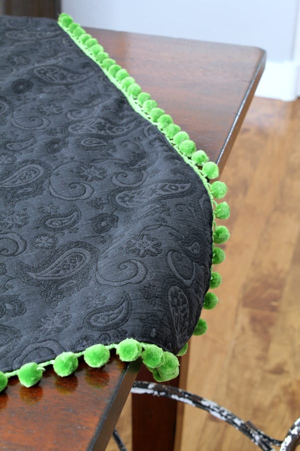 Black tablecloth with green pom poms.