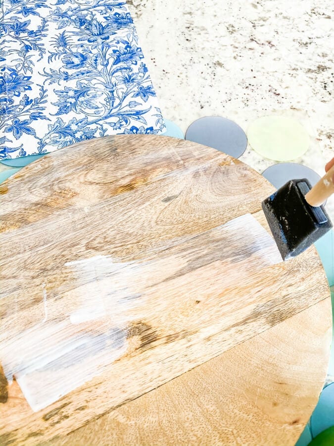 Applying Modge Podge to your wooden surface to prepare for a fun DIY!
