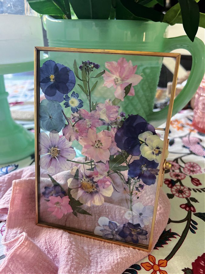 A gold frame with pressed flowers on display.