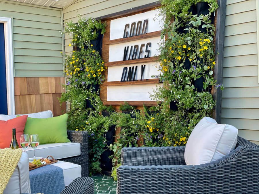 Welcome Home Saturday With A Life Unfolding | Welcome Home Saturday by popular Alabama lifestyle blog, She Gave It A Go: image of a back patio with grey wicker furniture with white cushions, and a marquees board surrounded by green and yellow flowering plants. 