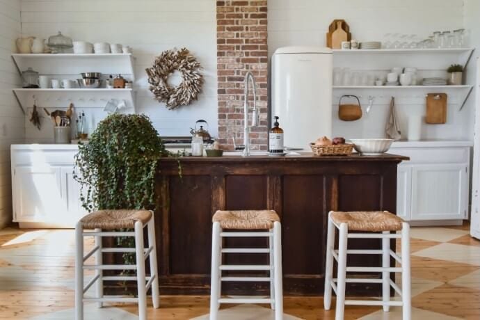 Welcome Home Saturday: Midcounty Journal |Welcome Home Saturday by popular Alabama lifestyle blog, She Gave It A Go: image of a farmhouse kitchen with white cupboards, white floating shelves, white stools, White fridge, and a dark wood kitchen island.