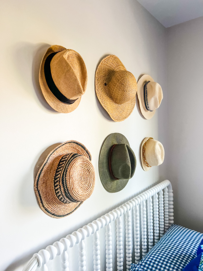 A set of 6 hats displayed above a bed.