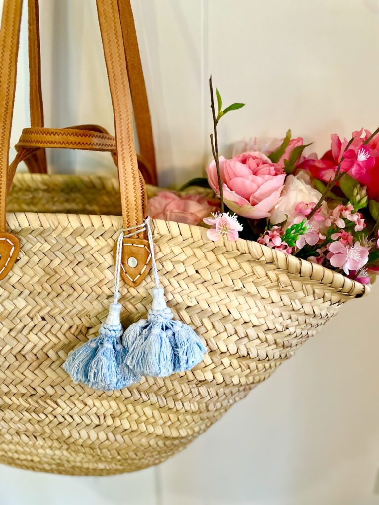 pink flowers in basket, blue tassel on handle