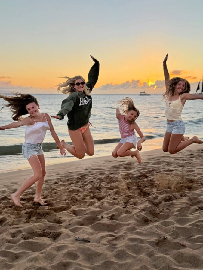 girls jumping on beach with cousins