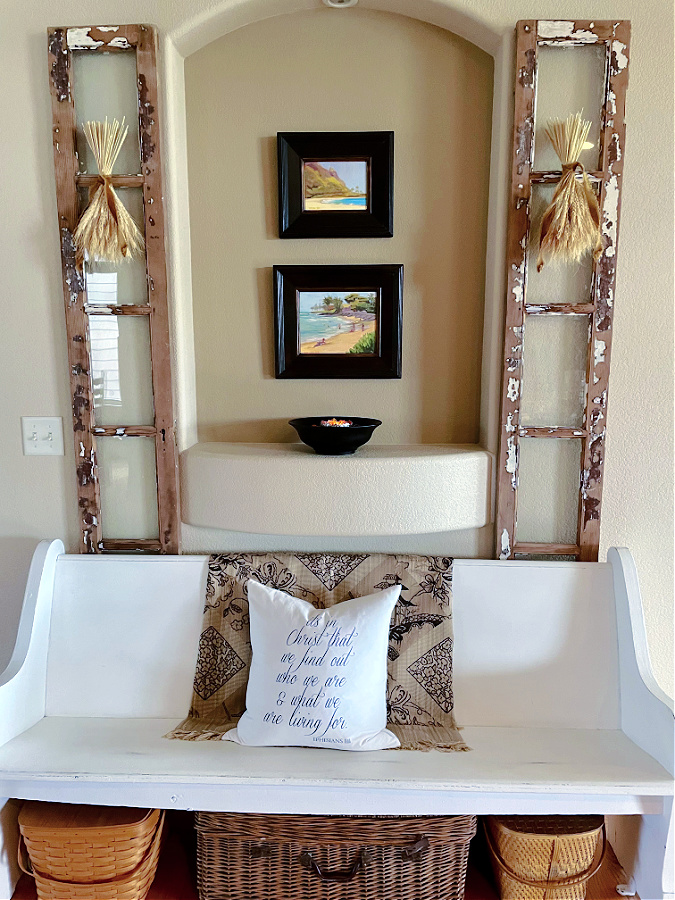 two vintage windows with wheat hanging on them and church pew between them
