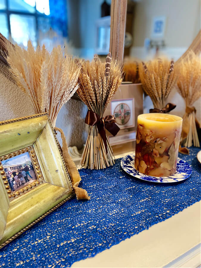 close up of picture frame, wheat bundles, candles on blue runner