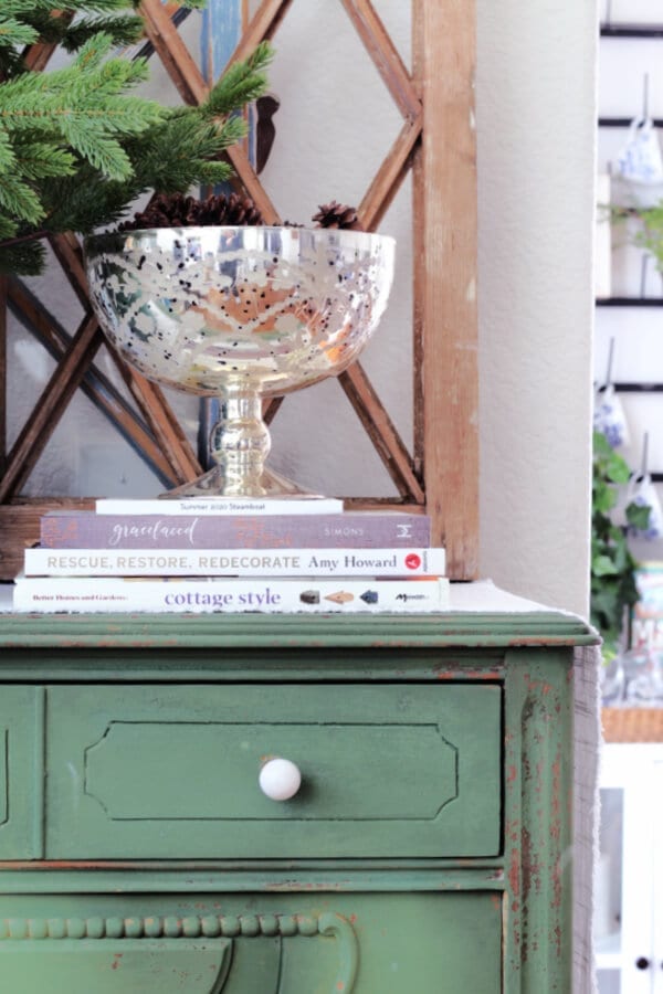 A winter vignette with books, pine cones and mercury glass.