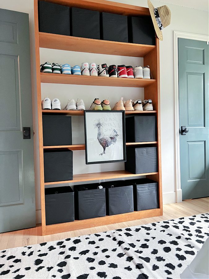 Built in wood shelves with shoes and black storage cubes