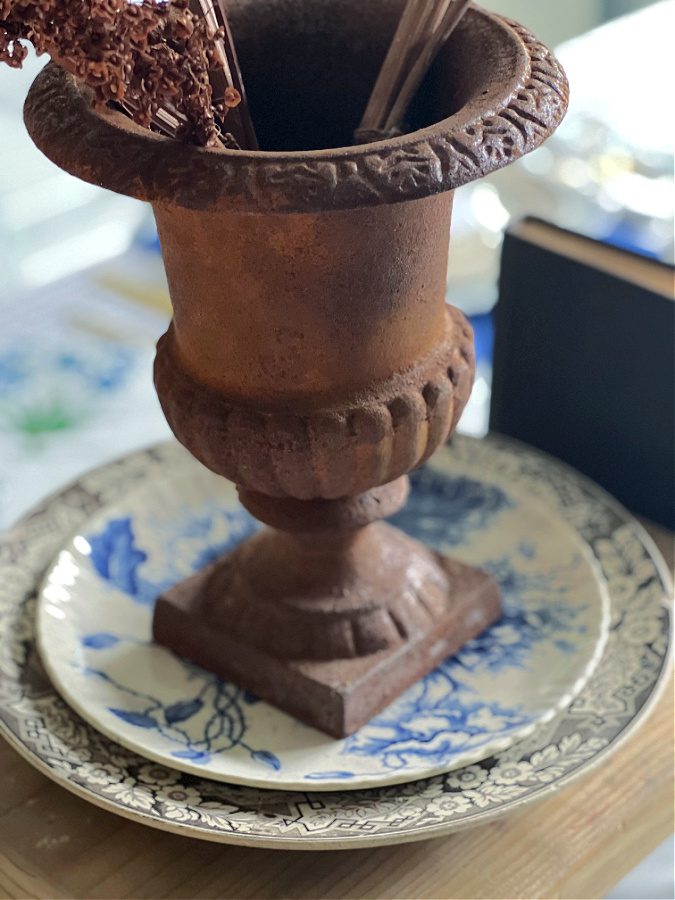 Rusty urn sitting on mismatched plates