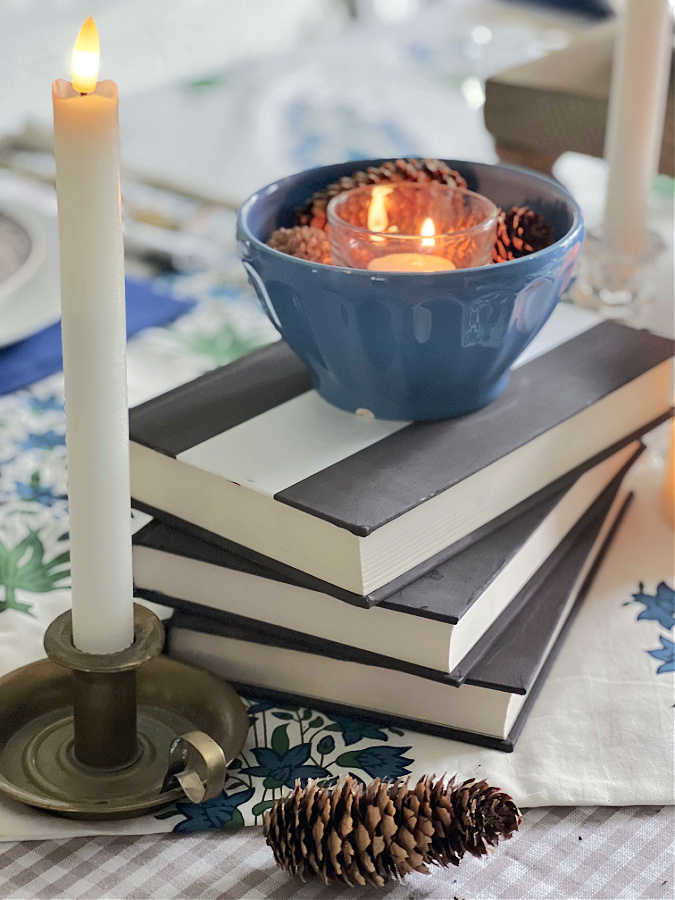 Books stacked with a bowl of pinecones and candles