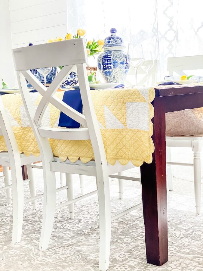 Un unexpected yellow and white quilts serves as the perfct tablecloth for this Mother's Day table.