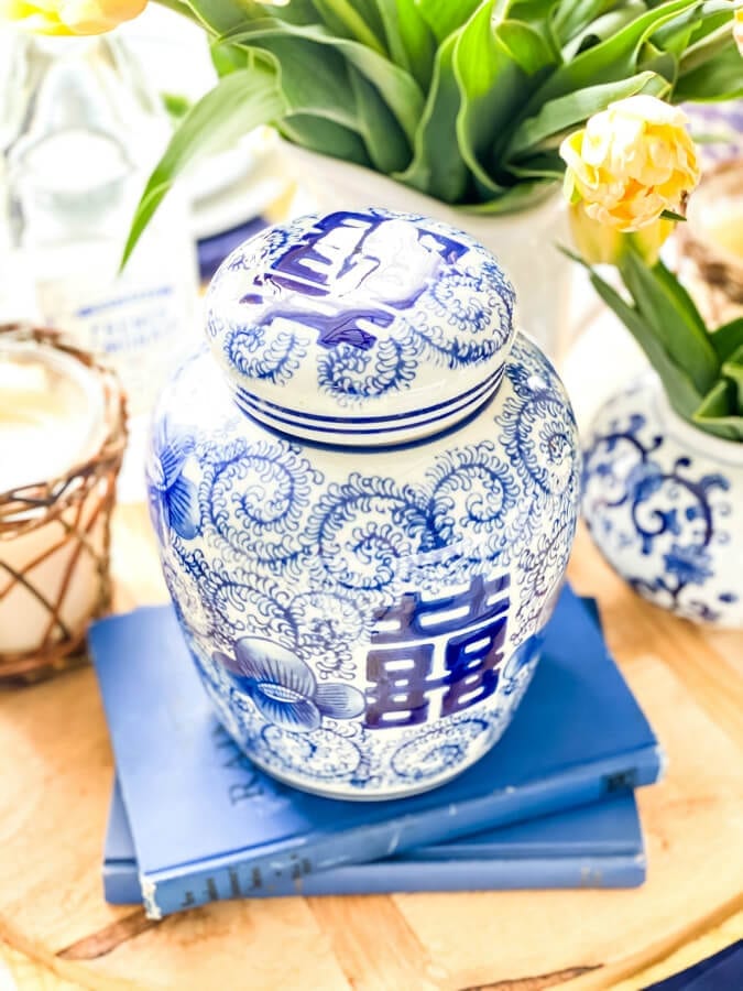 A blue ginger jar on books adds height to this pretty tablescape.
