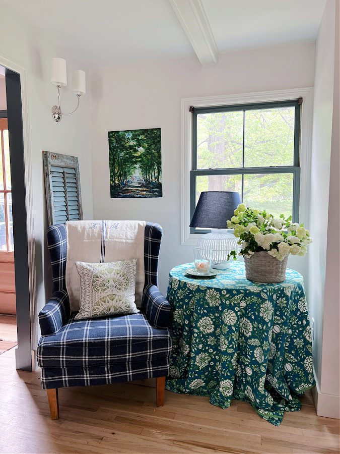 Our sitting area with our blue and white plaid chair next to a blue and green floral tablecloth covering a table. 