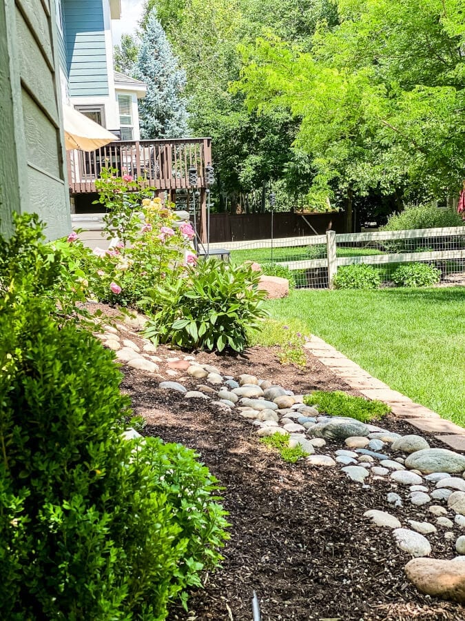 A river rock beds a beautiful touch to this backyard garden. AN easy DIY for anyone looking to ramp up their outdoor space.