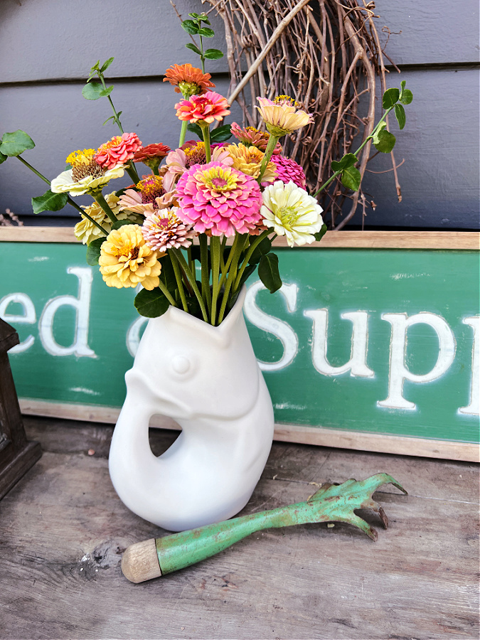 white gurgle pot pitcher with zinnias