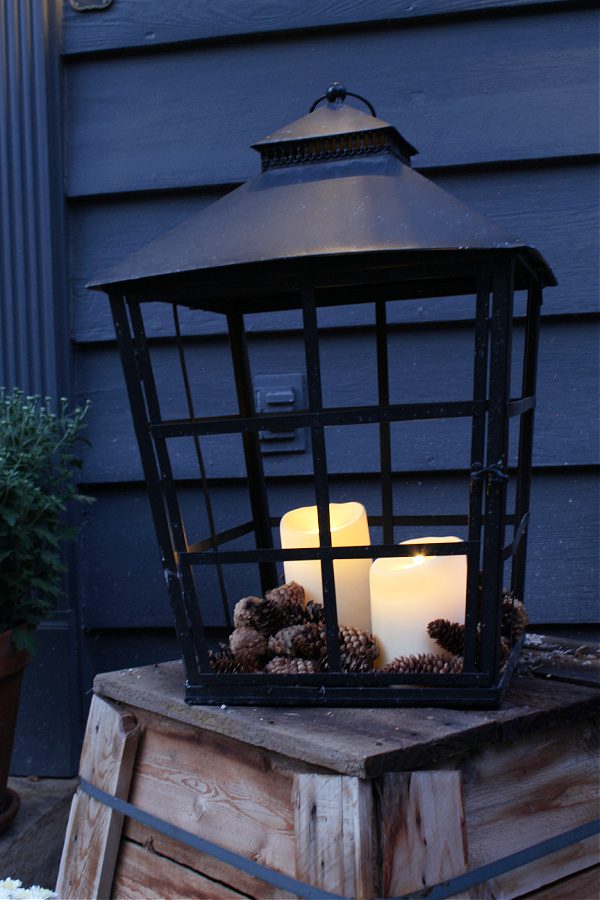 Large black lantern full of pincones and battery operated candles exudes Fall charm!