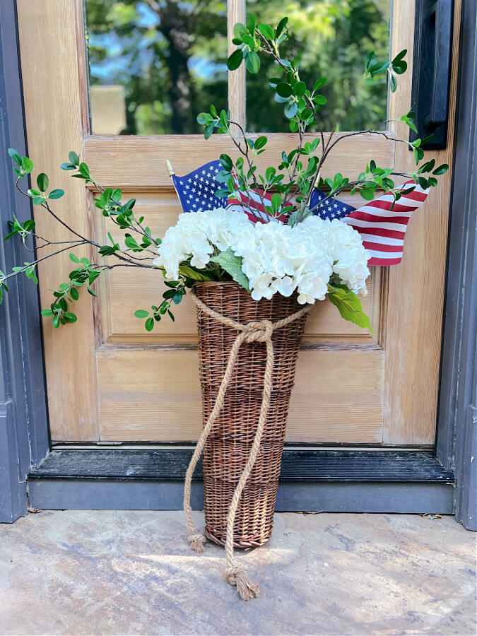 Flags in a door basket with white hydrangeas and green stems, perfect for the patriotic summer holidays.