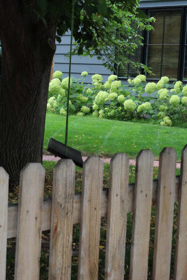 picket fence, hydrangeas and a wooden swing in our front yard