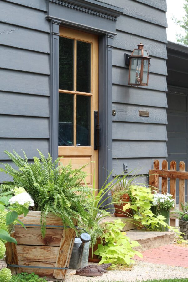 A wood front door with wondows and charm accents our peppercorn painted home.