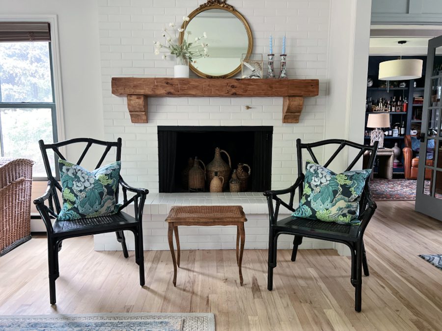 Two chairs with blue and green pillows in front of our white brick fireplace.