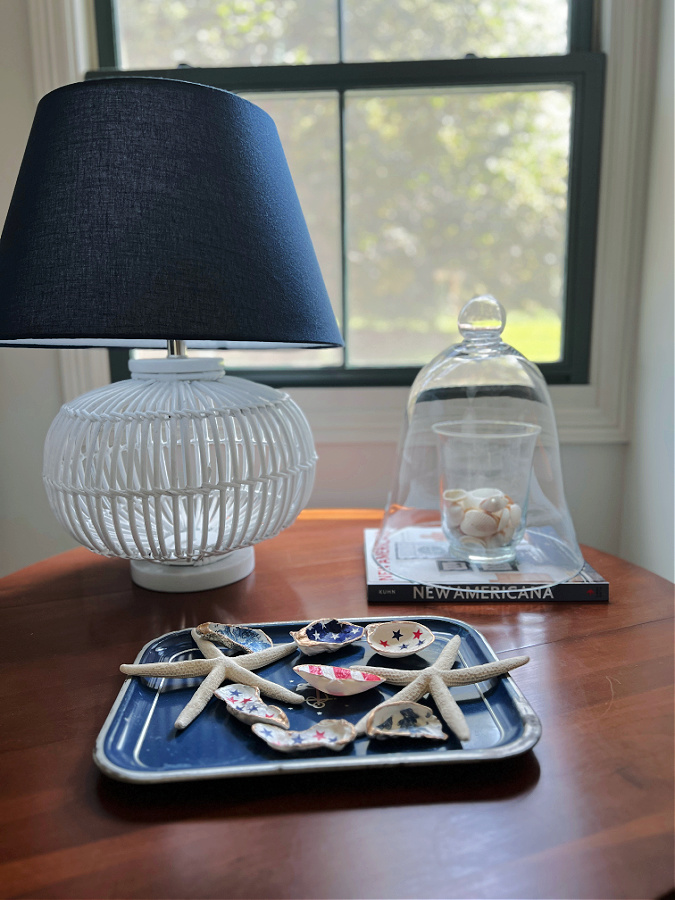 Decorating with a glass cloche on a coastal table for summer with a lamp