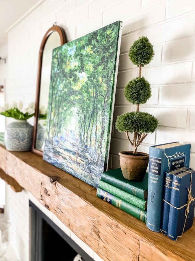 Original art, books and topiary decor on a Spring mantel.