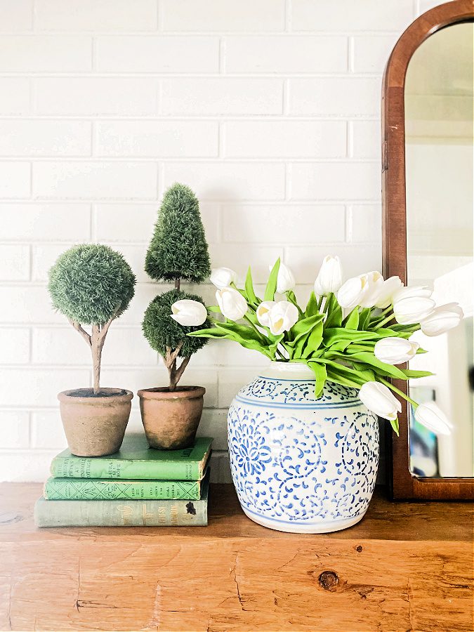 Topiaries, ginger jar with tulips, wood mantel and books for Spring decor.