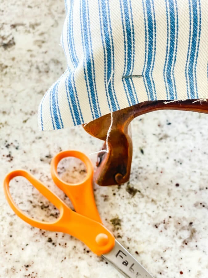 Staple and trim your fabric before adding the trim when recovering a footstool.