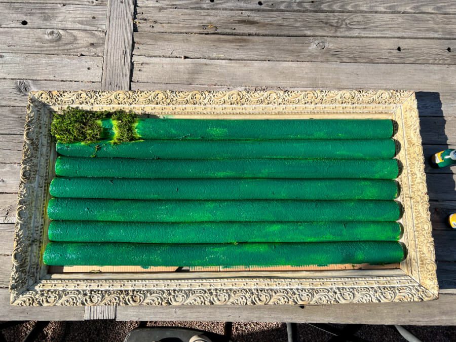 Painted green pool noodles in a vintage frame ready for moss to be added.