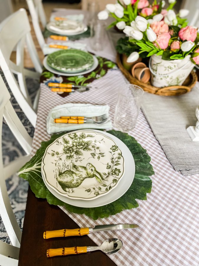 Faux cabbage placemats, gingham brown tablecloth and green and white bunny plates pop on this Easter tablescape.