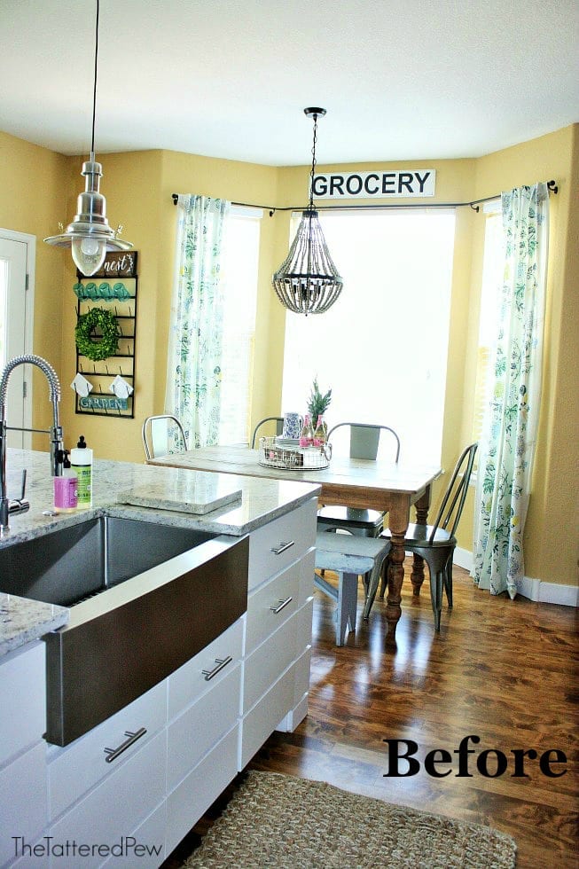 A white kitchen island on wood floors in a kitchen with yellow walls