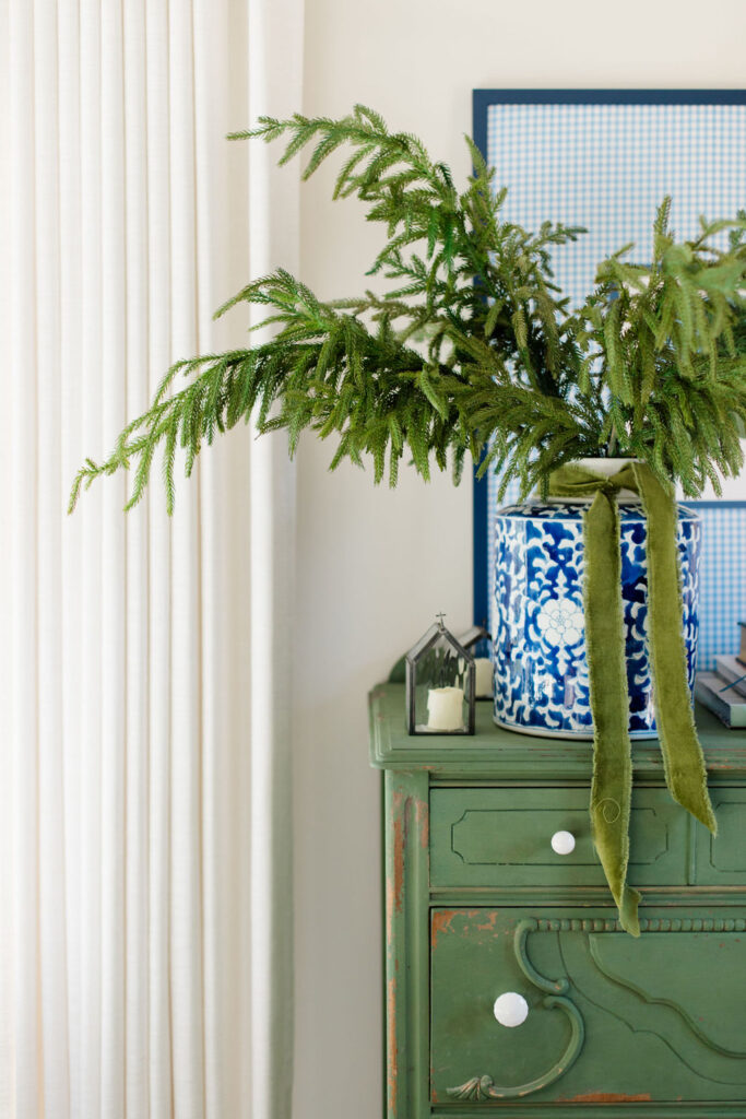 Boxwood green dresser with blue jar full of greenery