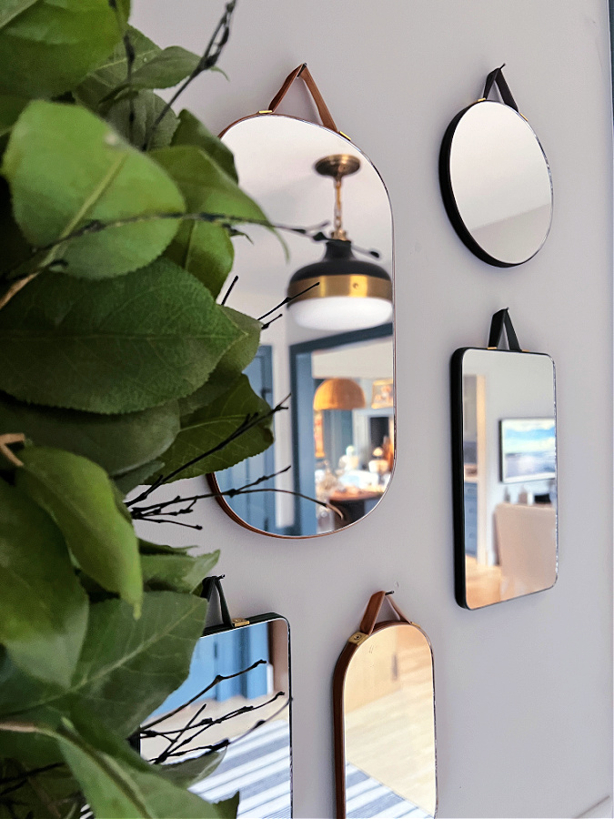 Collage of mirrors on wall next to green wreath.