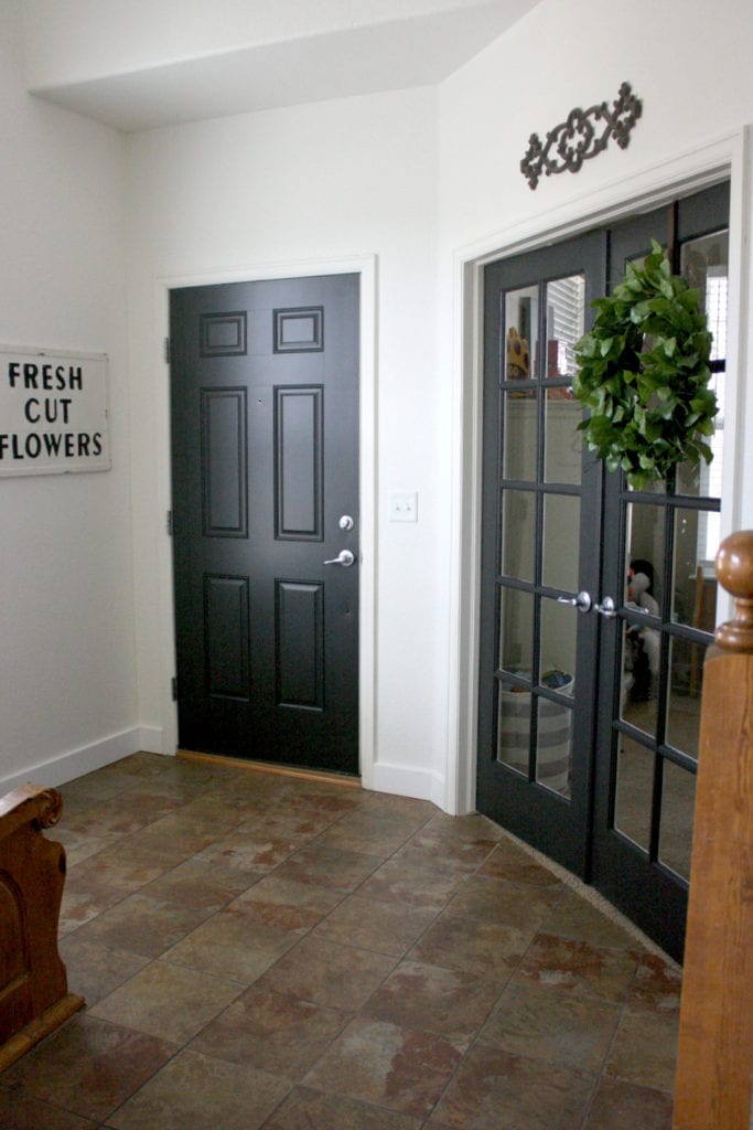 An entryway with white walls and black interior doors with white trim
