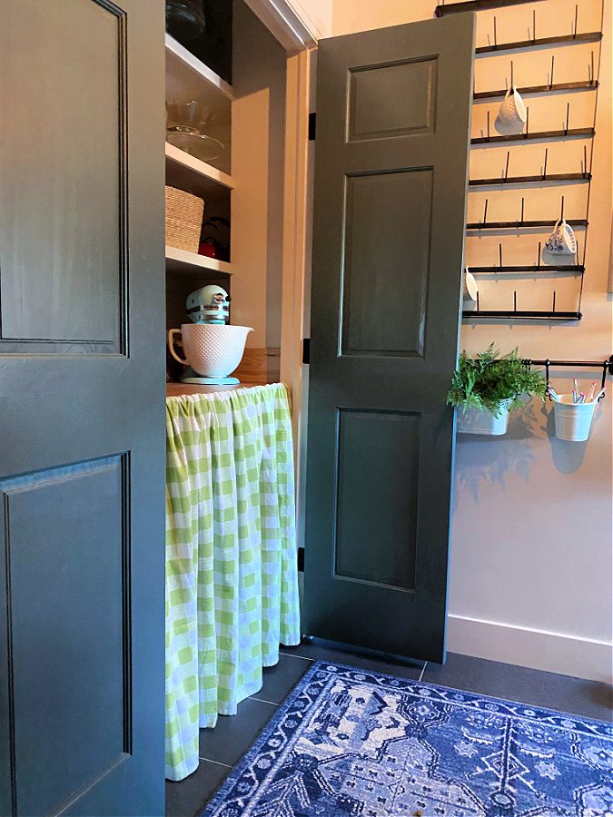 mudroom with pantry showing green and white curtain.