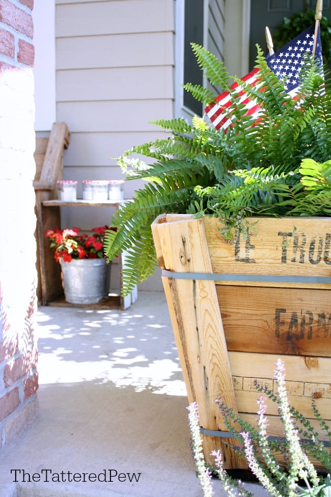 Patriotic touches on the porch with red flowers.