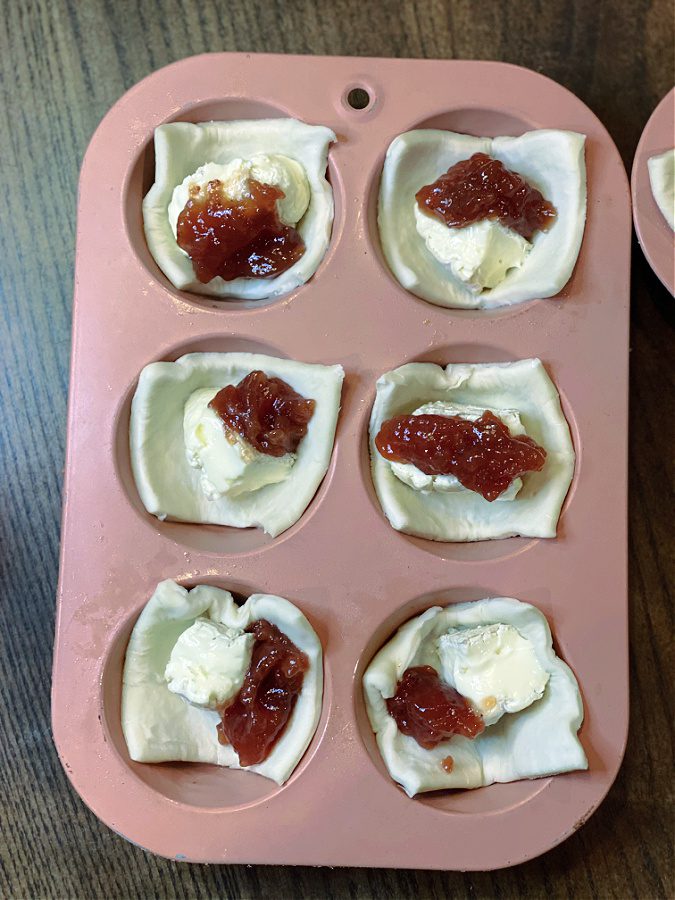 Adding strawberry fruit spread to the brie and puff pastry.