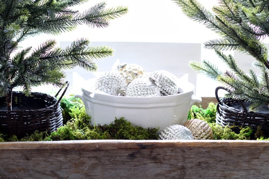 A simple and festive Christmas centerpiece using mercury glass ornaments and faux Christmas trees.
