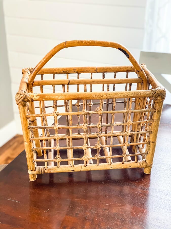 A vingtage, bamboo magazine rack on a wooden table.