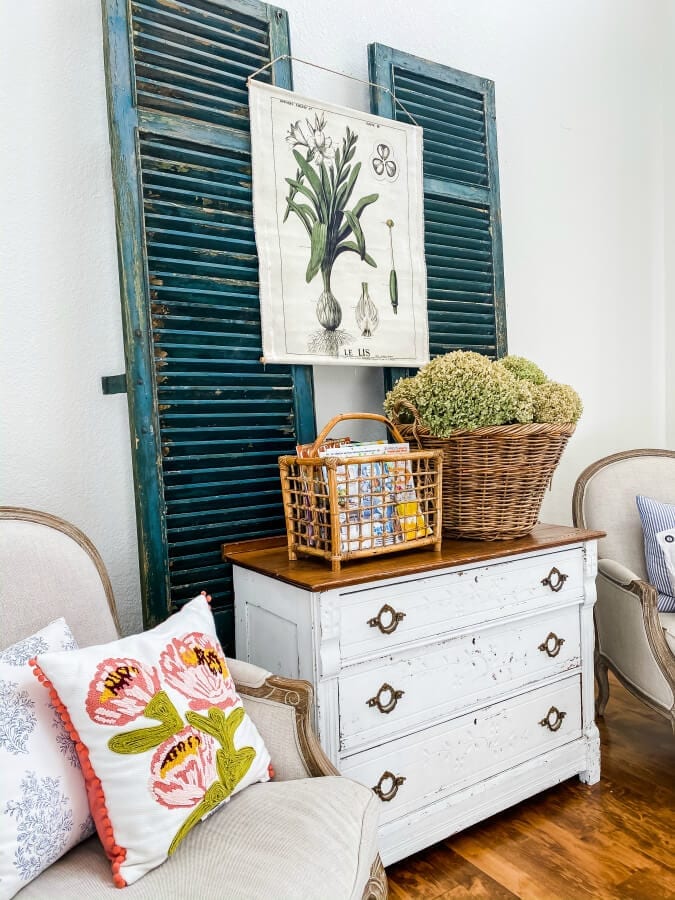 A vintage bamboo magazine rack sitting on top of a white dresser.