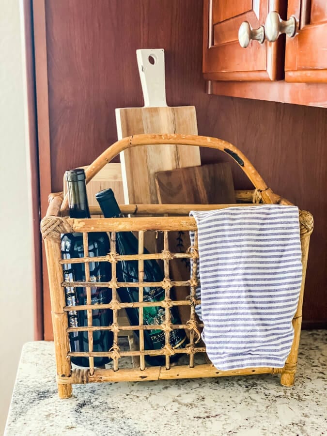 A vintage bamboo magazine rack filled with wine and cutting boards.
