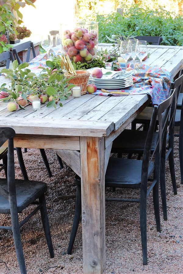 A simple outdoor Friendsgiving tablescape on a large wooden table with black metal cahirs.