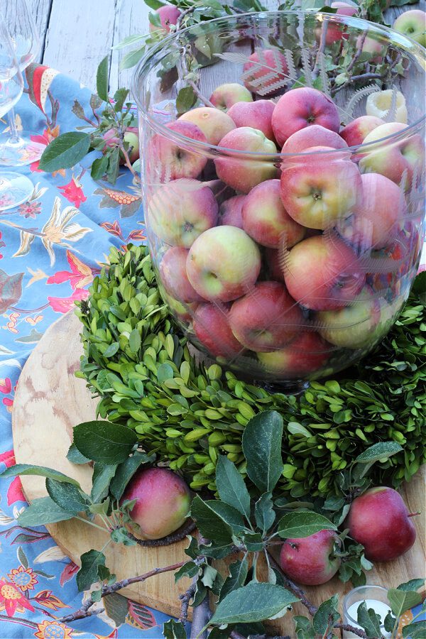 A Friendsgiving tablescape with fresh apples, candles and pops of blue.