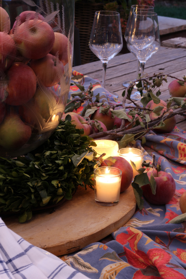 An evening table set with candles, wine glasses and a tablecloth.